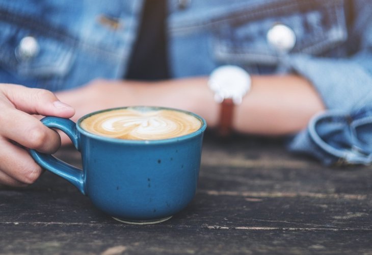 A persons sits with a milky coffee in front of them