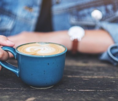 A persons sits with a milky coffee in front of them