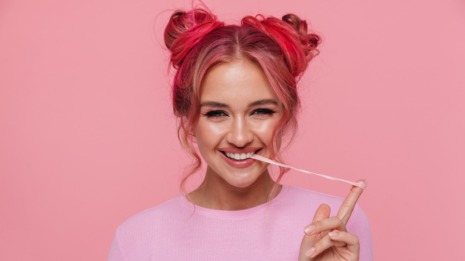 A woman pulls a string of chewing gum from her mouth