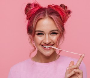 A woman pulls a string of chewing gum from her mouth