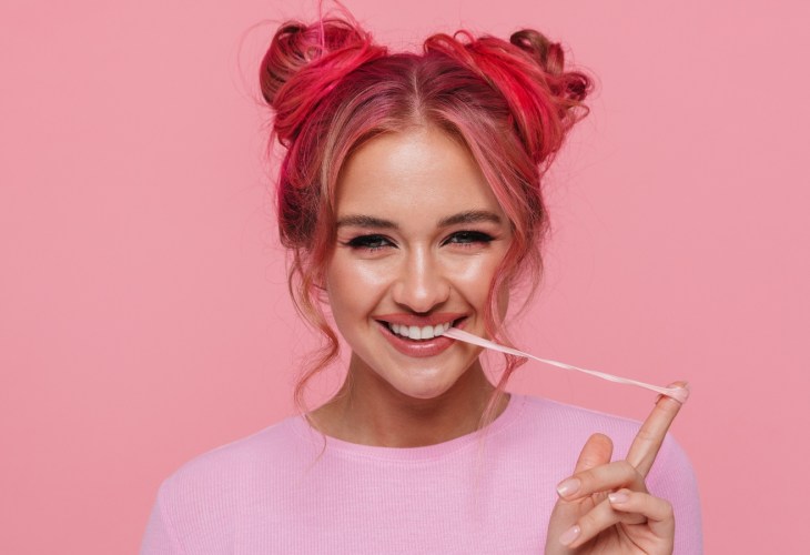 A woman pulls a string of chewing gum from her mouth