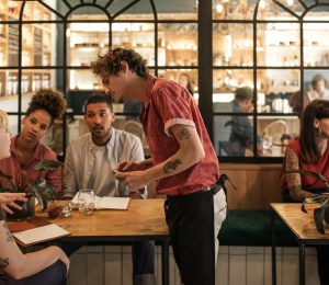 People sat at a table ordering food from menus