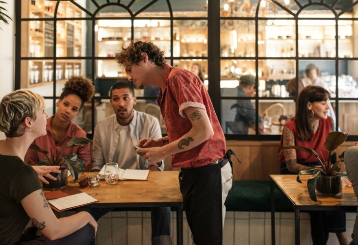 People sat at a table ordering food from menus