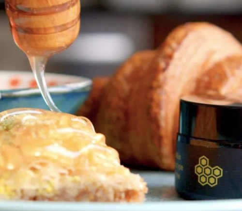 vegan honey spread over croissant using a honey dropper