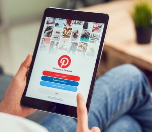 A person holds a tablet showing the Pinterest log-in page