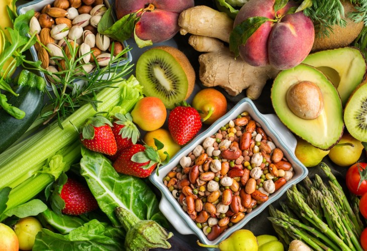 Overhead view table scene on a wooden background. Super food concept with green vegetables, berries, whole grains, seeds, spices and nutritious items.