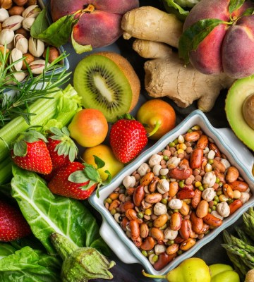 Overhead view table scene on a wooden background. Super food concept with green vegetables, berries, whole grains, seeds, spices and nutritious items.