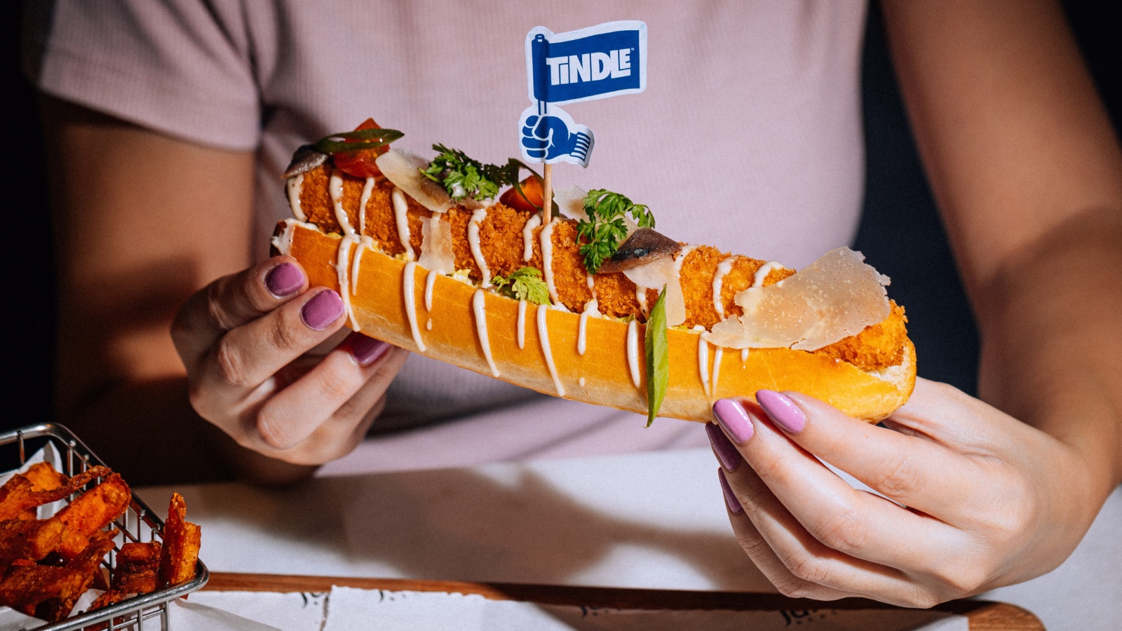 woman holding a TiNDLE chicken hot dog