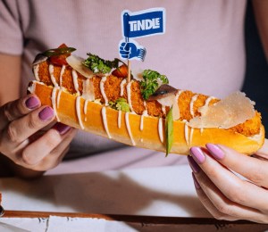 woman holding a TiNDLE chicken hot dog