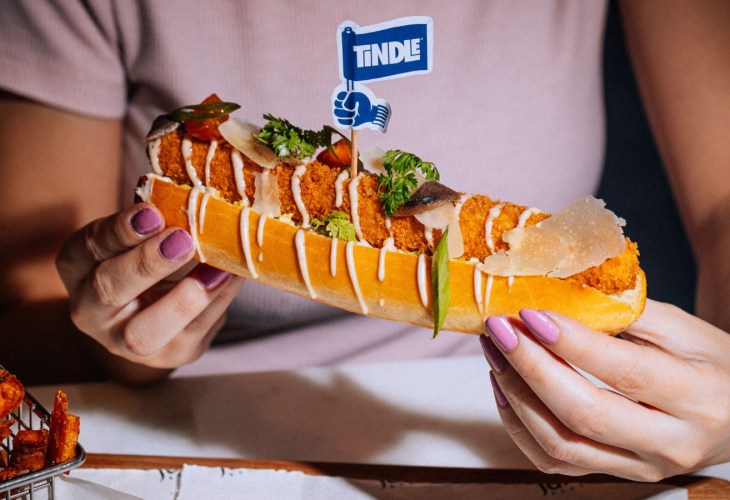 woman holding a TiNDLE chicken hot dog