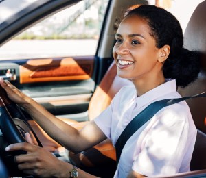 A woman smiling while she drives a car