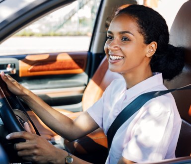 A woman smiling while she drives a car