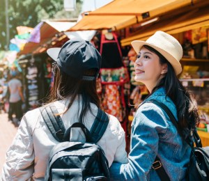 Two friends walking through an outdoor market