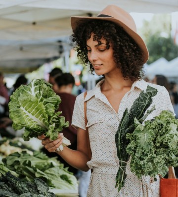 A person choosing between two vegetables at a market