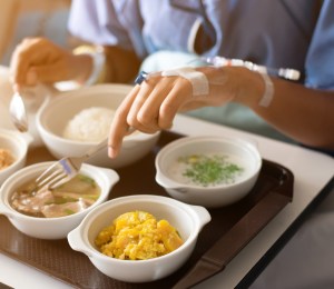 Woman wearing a blue dress, eating on the bed in the hospital