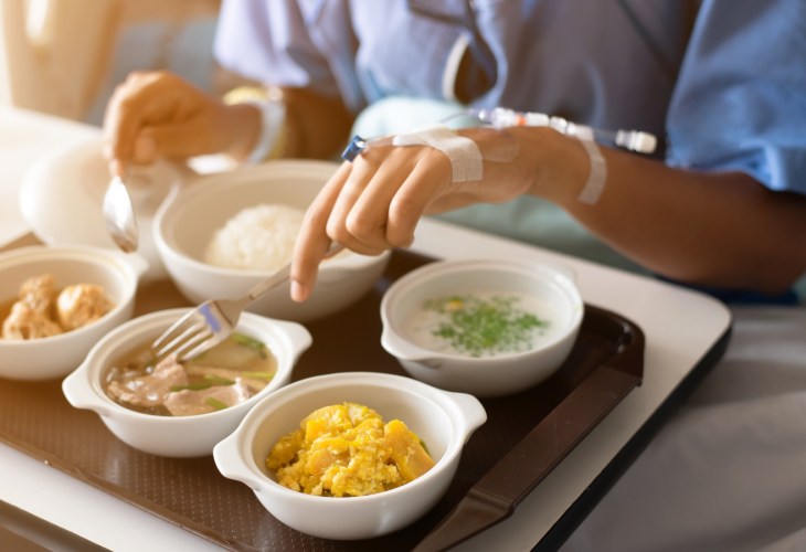 Woman wearing a blue dress, eating on the bed in the hospital