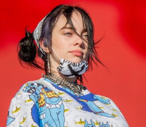 Billie Eilish on stage with a mask on her chin.