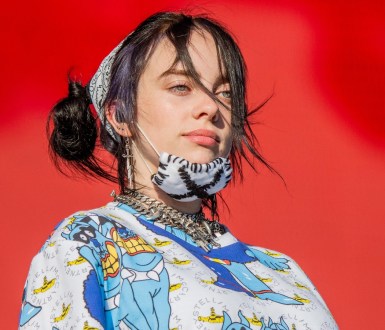 Billie Eilish on stage with a mask on her chin.